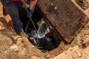 Breaking up aged concrete wastewater outlet in an old septic tank, updating a septic system, horizontal aspect